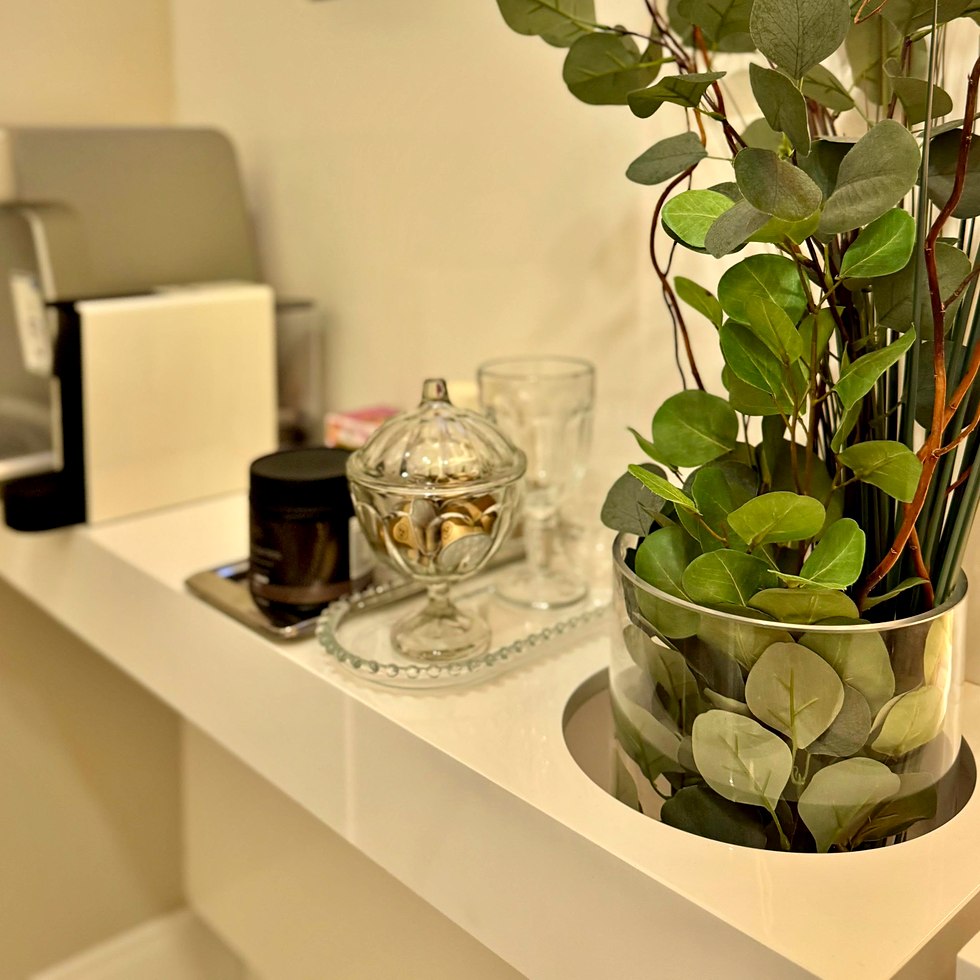 Detalhe da recepção de uma clínica parceira: vaso de folhagem, potiche de vidro e café à espera